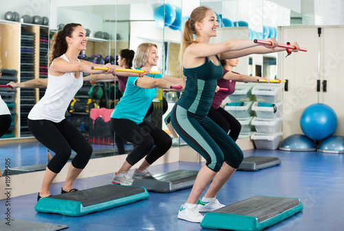 Females working out on aerobic step platform in modern gym