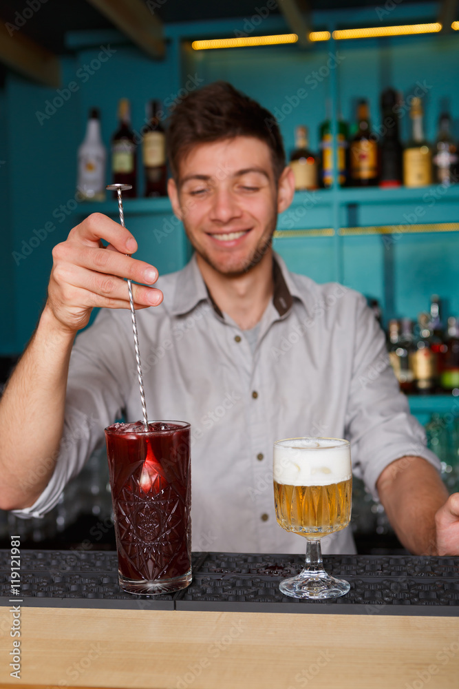 Barman in bar interior making alcohol berry cocktail