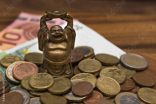 Canvas-taulu Mascot netske Hotei coins Euro banknotes on a wooden table