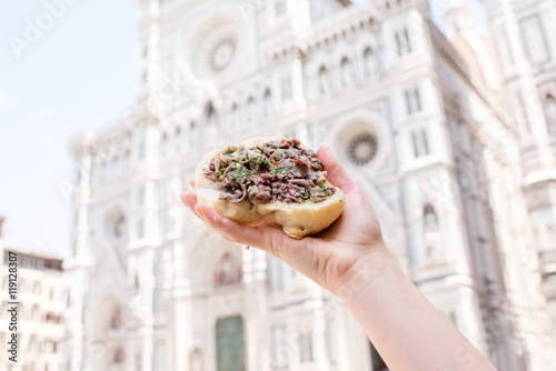 Holding lampredotto sandwich on the Duomo background in Florence. Lampredotto is a typical Florentine dish made from the stomach of a cow