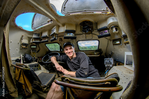 A man sits in a military BTR on the driver's seat photo
