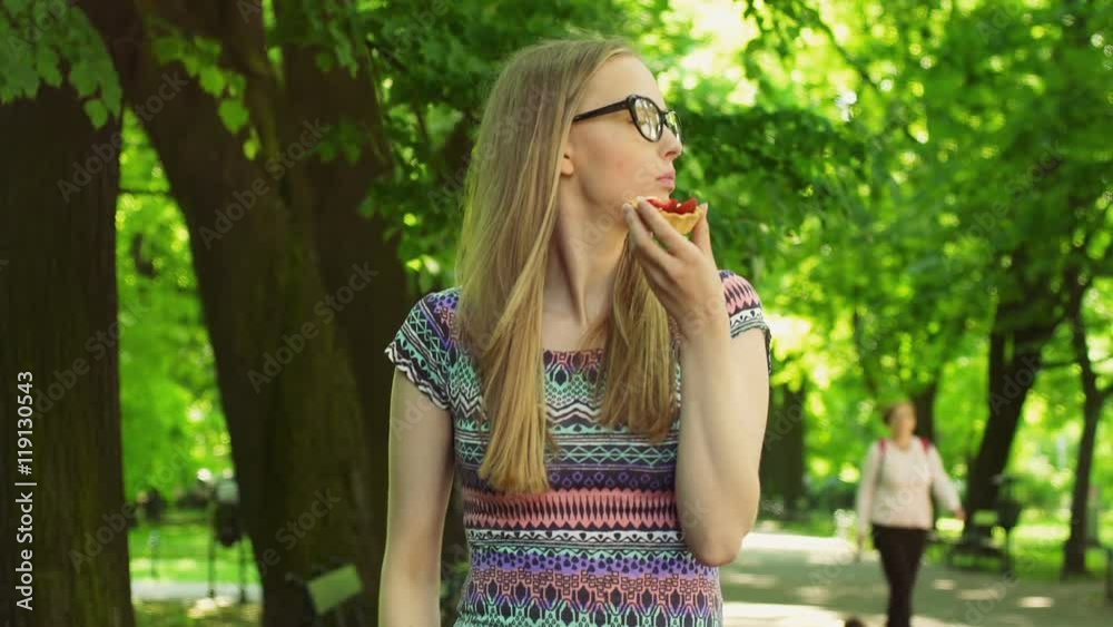 Pretty girl eating cookie and smiling to the camera in the park
Pretty girl eating cookie and smiling to the camera in the park
