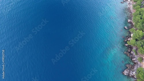 Aerial view of clear turquoise sea and rocky coastline in the morning