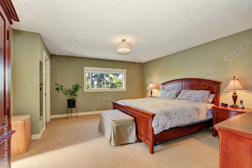 View of king size wooden bed in olive bedroom interior.