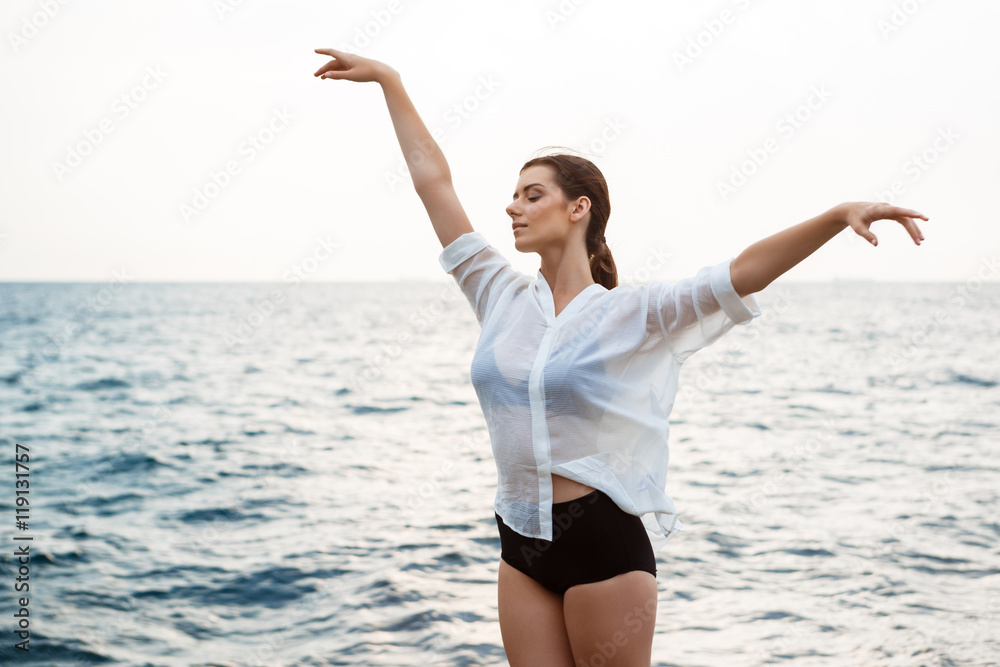 Young beautiful ballerina dancing and posing outside, sea background. Young beautiful ballerina dancing and posing outside, sea background.