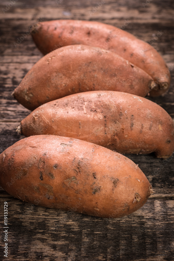 Raw sweet potatoes on wooden background closeup Raw sweet potatoes on wooden background closeup