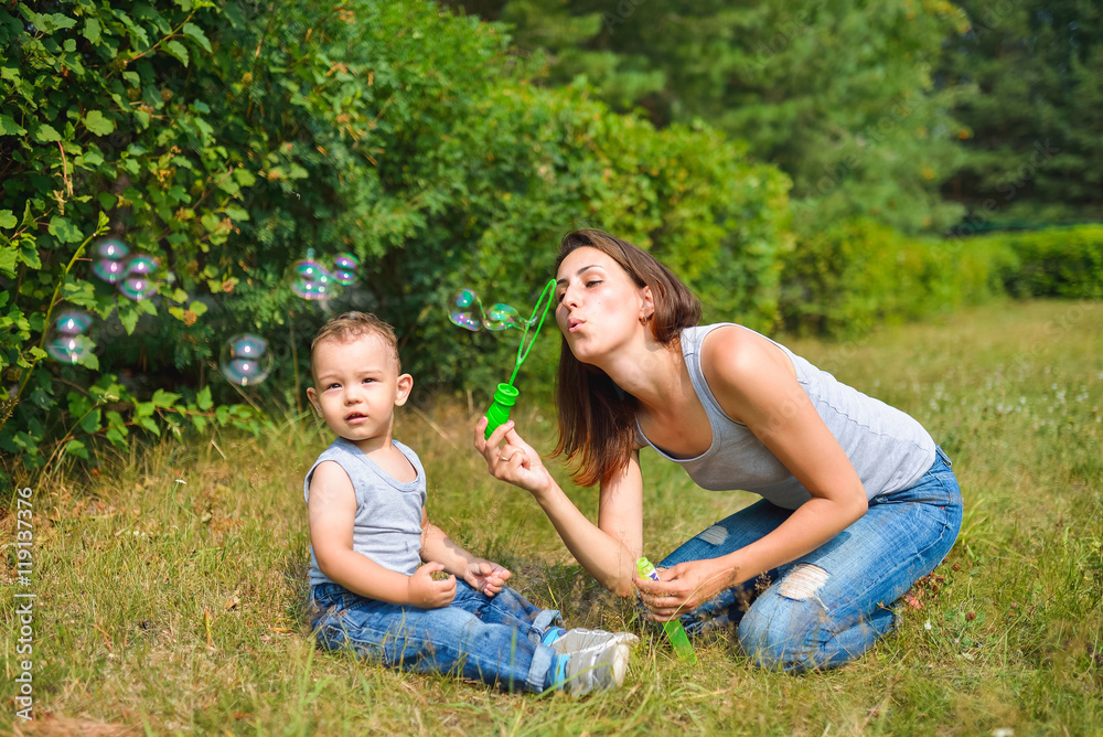 Fototapeta premium Mother with her son blowing bubbles at summer day