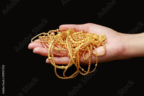 Hand holding group of gold jewelry isolate on black
