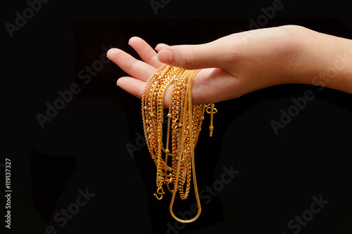 woman hand hold group of gold necklace jewelry isolate on black