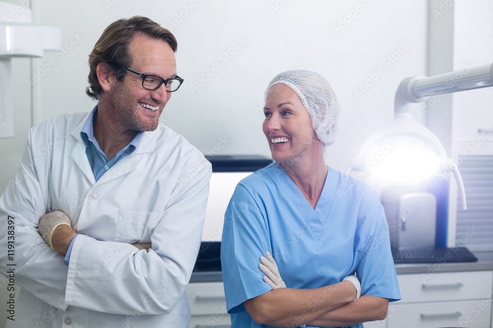 Obraz premium Smiling dentist and dental assistant standing with arms crossed