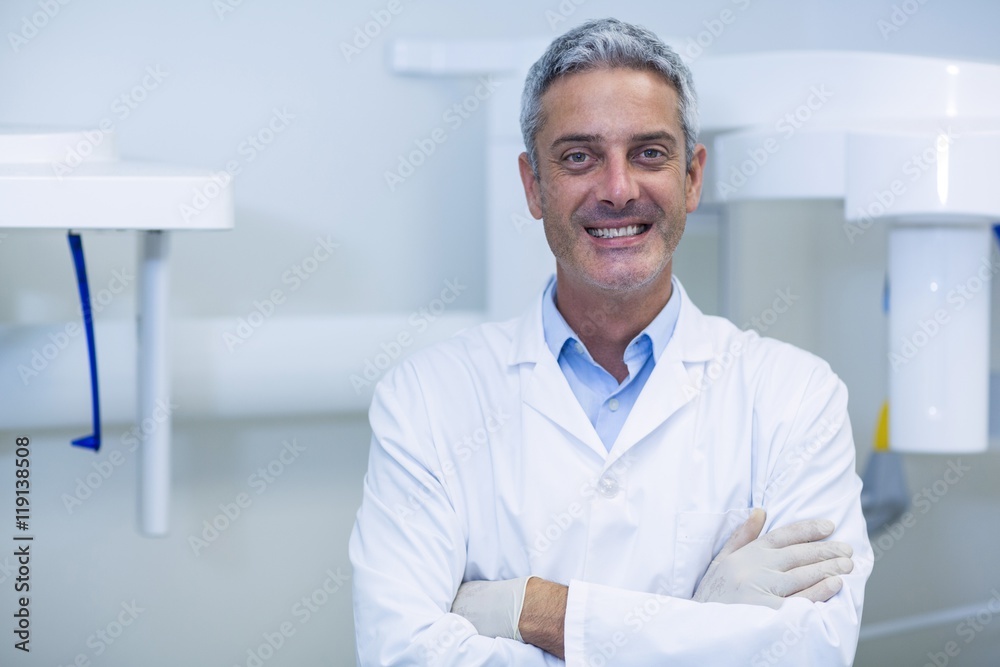Smiling dentist standing in dental clinic