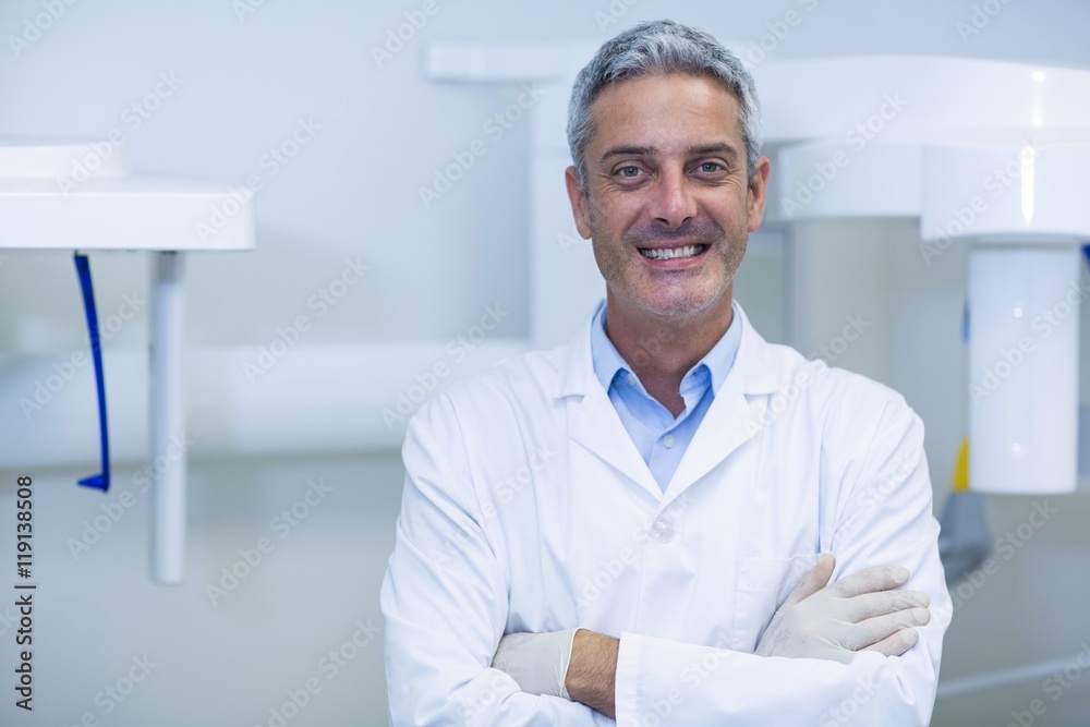 Smiling dentist standing in dental clinic Smiling dentist standing in dental clinic