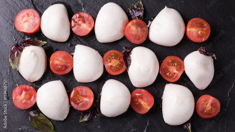 mozzarella balls with tomatoes and basil on slate board