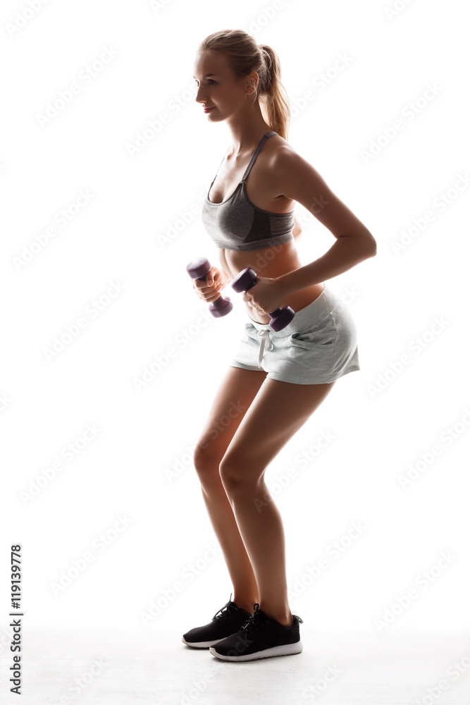Beautiful sportive girl training with dumbbells over white background. Beautiful sportive girl training with dumbbells over white background.