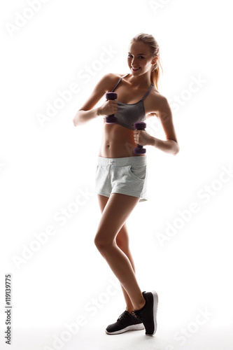 Beautiful sportive girl training with dumbbells over white background.