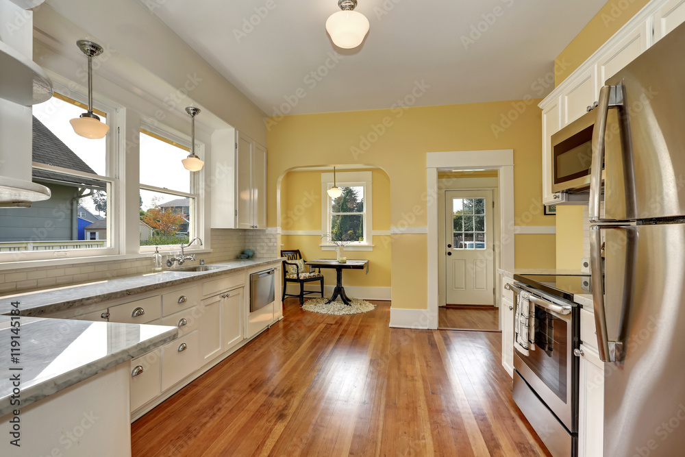Kitchen interior with white cabinets, yellow walls and wood floor