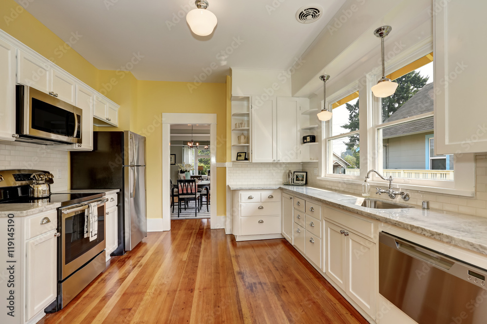 Kitchen interior with white cabinets, yellow walls and wood floor Kitchen interior with white cabinets, yellow walls and wood floor