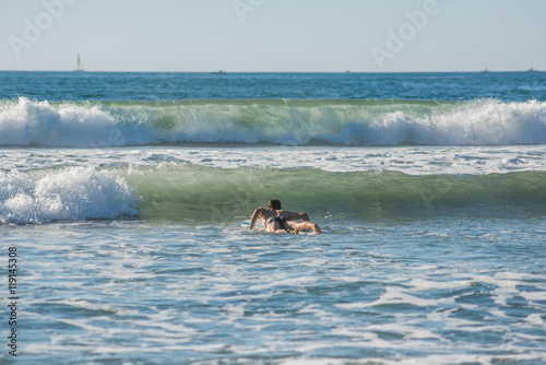 Student beginner novice male surfer getting ready for upcoming wave California pacific ocean