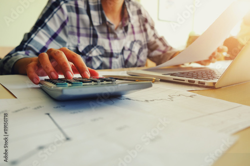 Asian Business woman using a calculator to calculate the numbers photo