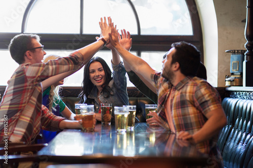 Canvas Print happy friends with beer making high five at pub