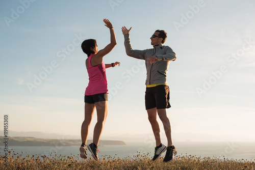 Bild auf Leinwand Fitness running couple giving five while jumping outdoor after running training