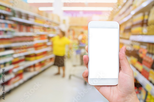 female hand holding mobile smartphone over supermarket backgroun