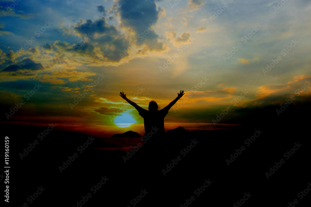 single adult woman silhouette on rock relaxing in sunset