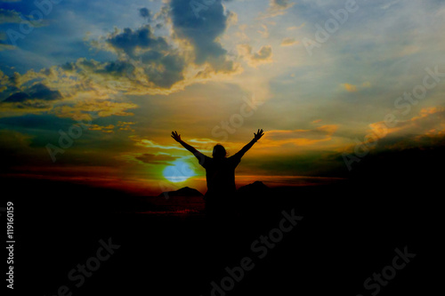 single adult woman silhouette on rock relaxing in sunset