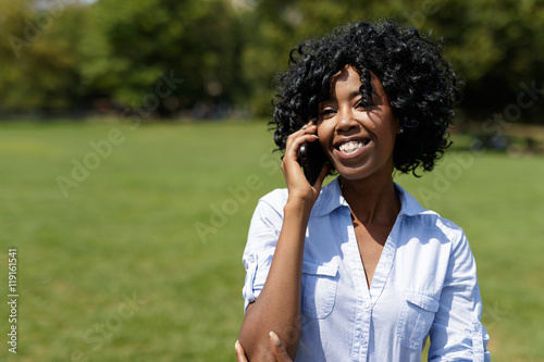 Black woman in a park talking on cell phone 