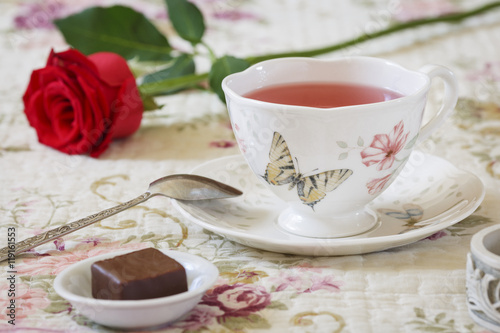 Fruit tea in a porcelain dish, chocolates and red rose