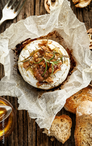 Baked Camembert with walnuts, honey  and rosemary on wooden rustic table, top view