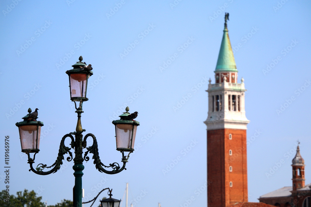 Pigeons on a traditional lamp in Venice, Italy. Church of San Giorgio Maggiore in the background.