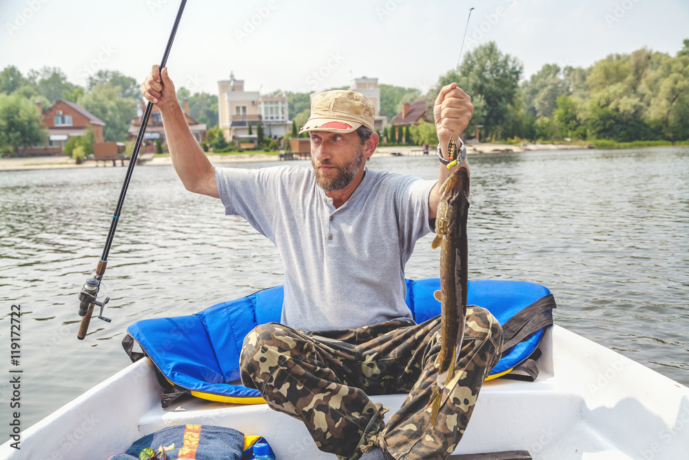 fisherman in boat holding spinning and pike fisherman in boat holding spinning and pike