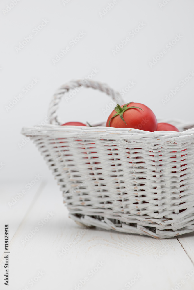 tomatoes in a white basket on a white background