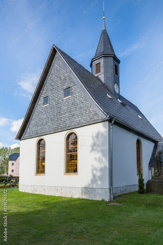 Fototapeta premium Village church in Saxony, Germany, a steeple and slate roof, cloudy sky/Village church