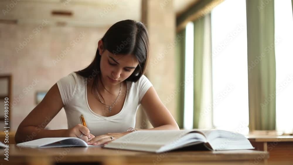 beautiful girl doing notes from a book in the library beautiful girl doing notes from a book in the library
