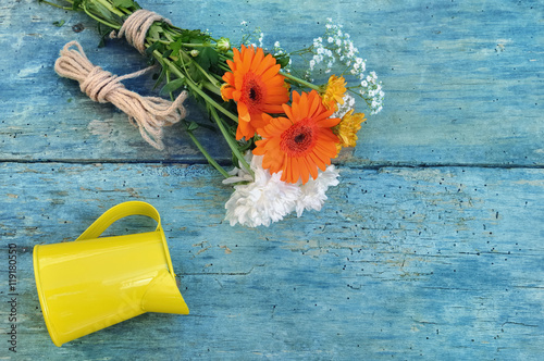 bouquet de fleur et bidon sur planche bois bleue
