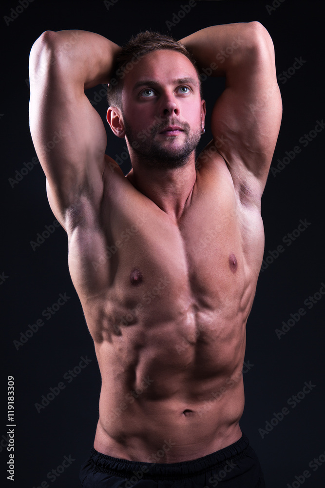 Fototapeta premium portrait of young handsome muscular man posing over grey