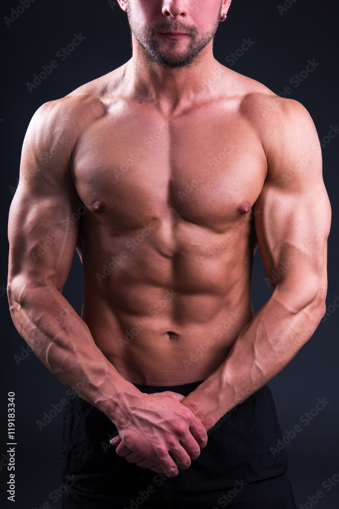 beautiful muscular body of young man posing over grey beautiful muscular body of young man posing over grey