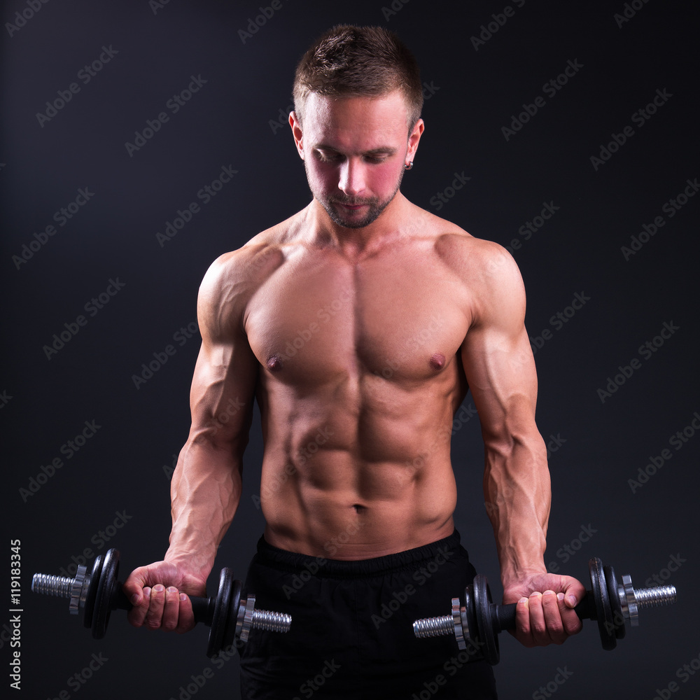 portrait of young handsome muscular man with dumbbells over grey