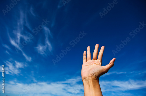 Outstretched arm against a blue sky. Concept greeting.