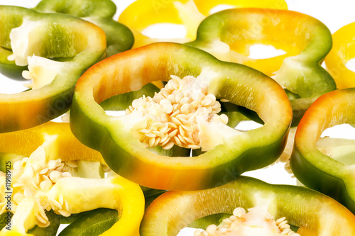 Slices of yellow and green pepper vegetables on white background