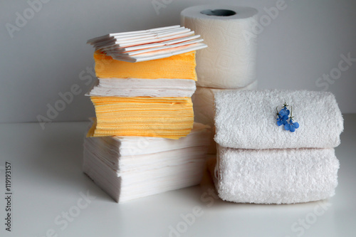 Stacks of white loop towels, paper tissues, paper napkins, toilet paper - composition with little blue flowers on white board.Copy space.
 photo