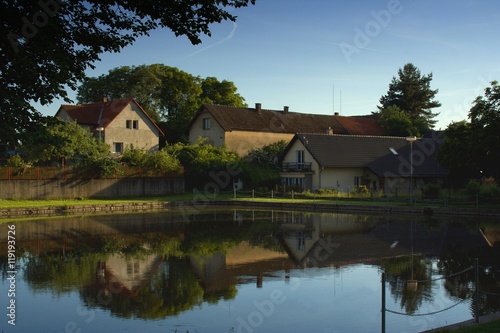 Typical czech small village plaza with pond and trees around.