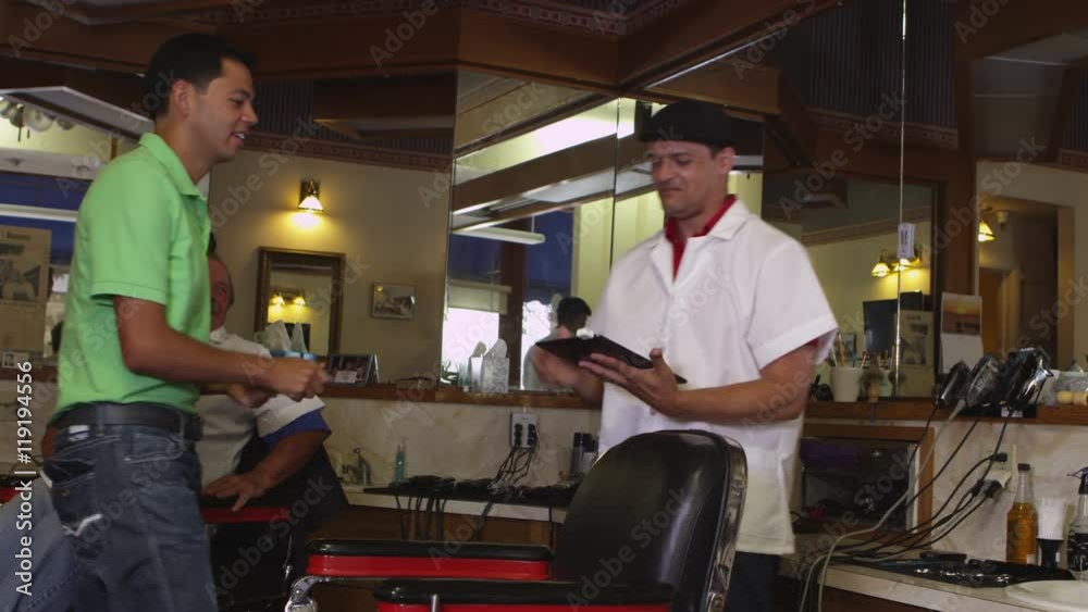 Man paying for new haircut at barber shop Man paying for new haircut at barber shop