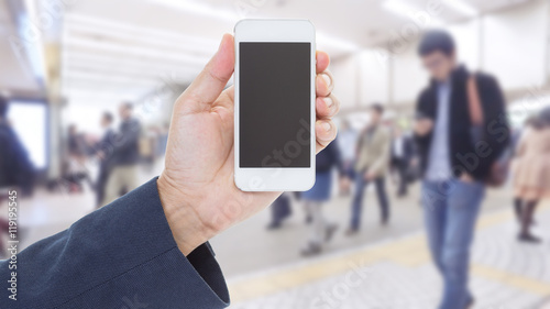 Hand holding mobile phone with blurred image of people use for b