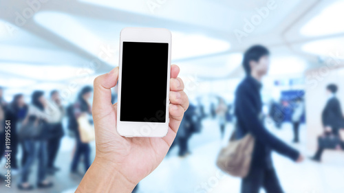 Hand holding mobile phone with blurred image of people use for b