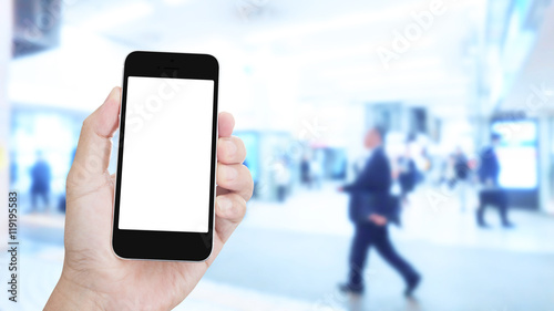 Hand holding mobile phone with blurred image of people use for b