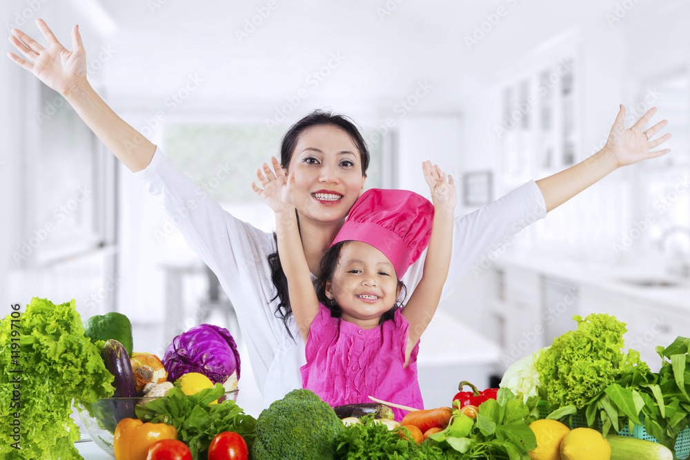 Mother and daughter with vegetables in kitchen Mother and daughter with vegetables in kitchen