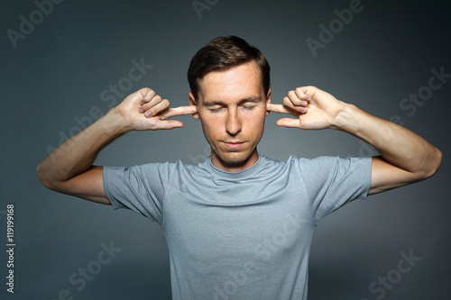 Young man stopped his ears with fingers.